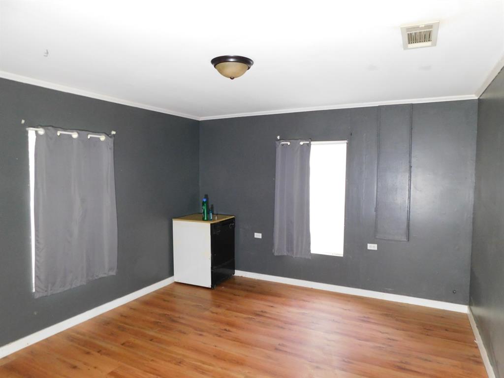 901 North Arkansas Street Springhill, LA 71075 - Photo 22 of 26 Spare room featuring baseboards, ornamental molding, visible vents, and wood finished floors