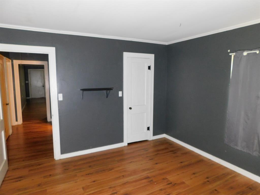 901 North Arkansas Street Springhill, LA 71075 - Photo 23 of 26 Empty room featuring baseboards, wood finished floors, and ornamental molding