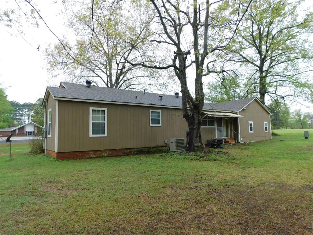 901 North Arkansas Street Springhill, LA 71075 - Photo 9 of 26 Back of house featuring entry steps, central air condition unit, roof with shingles, and a yard