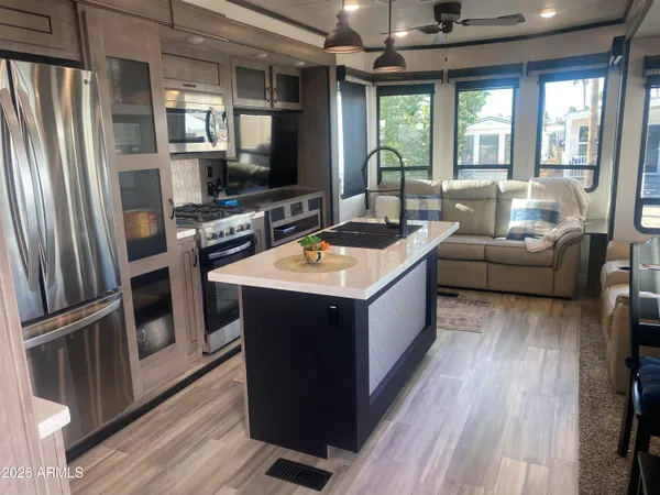 a kitchen with stainless steel appliances granite countertop a refrigerator a sink dishwasher a stove and a dining table with wooden floor