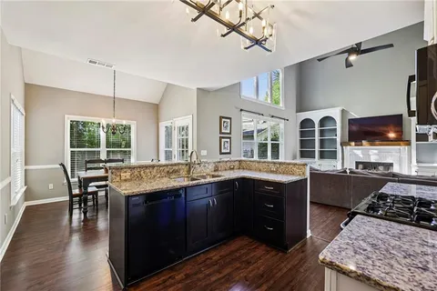 a kitchen with stainless steel appliances granite countertop a stove and a table chairs in it