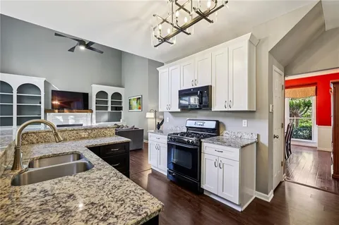 a kitchen with stainless steel appliances granite countertop a sink dishwasher stove top oven and cabinets with wooden floor