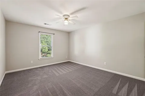 an empty room with windows and chandelier fan