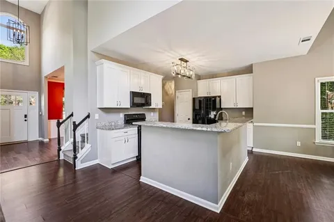 a kitchen with stainless steel appliances kitchen island granite countertop a stove top oven a sink a dining table and chairs with wooden floor