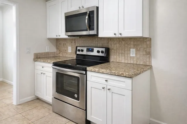 a kitchen with stainless steel appliances granite countertop white cabinets a microwave and a stove