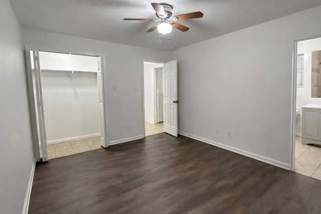 an empty room with wooden floor closet and windows