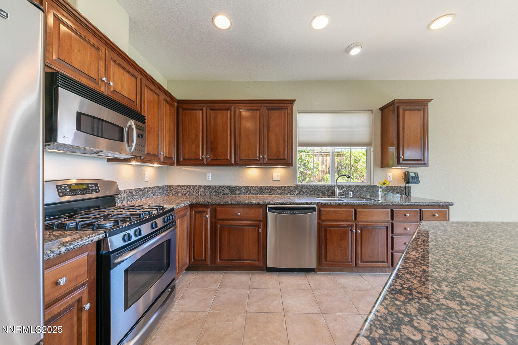 8890 Chipshot Trail Reno, NV 89523 - Photo 18 of 36 a kitchen with stainless steel appliances granite countertop a stove top oven a sink dishwasher a microwave oven and a dining table with wooden floor