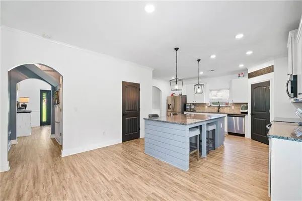 a kitchen with kitchen island wooden floor center island and stainless steel appliances