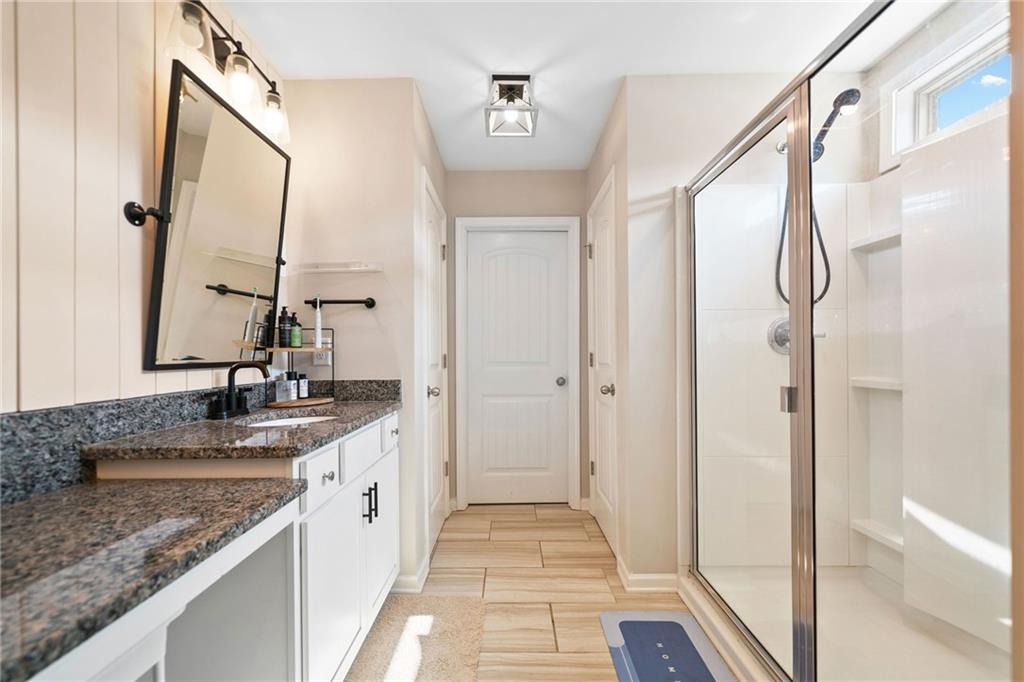 13 Four Feathers Lane Northeast Rydal, GA 30171 - Photo 34 of 51 a bathroom with a granite countertop sink a mirror and a shower