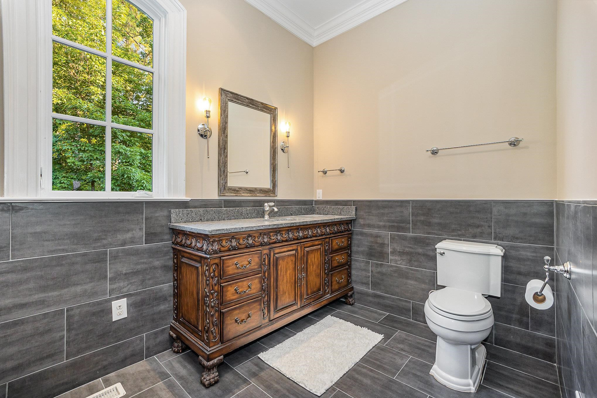 7728 Grace Cove Lane Raleigh, NC 27613 - Photo 46 of 82 a bathroom with a granite countertop toilet a sink and a mirror
