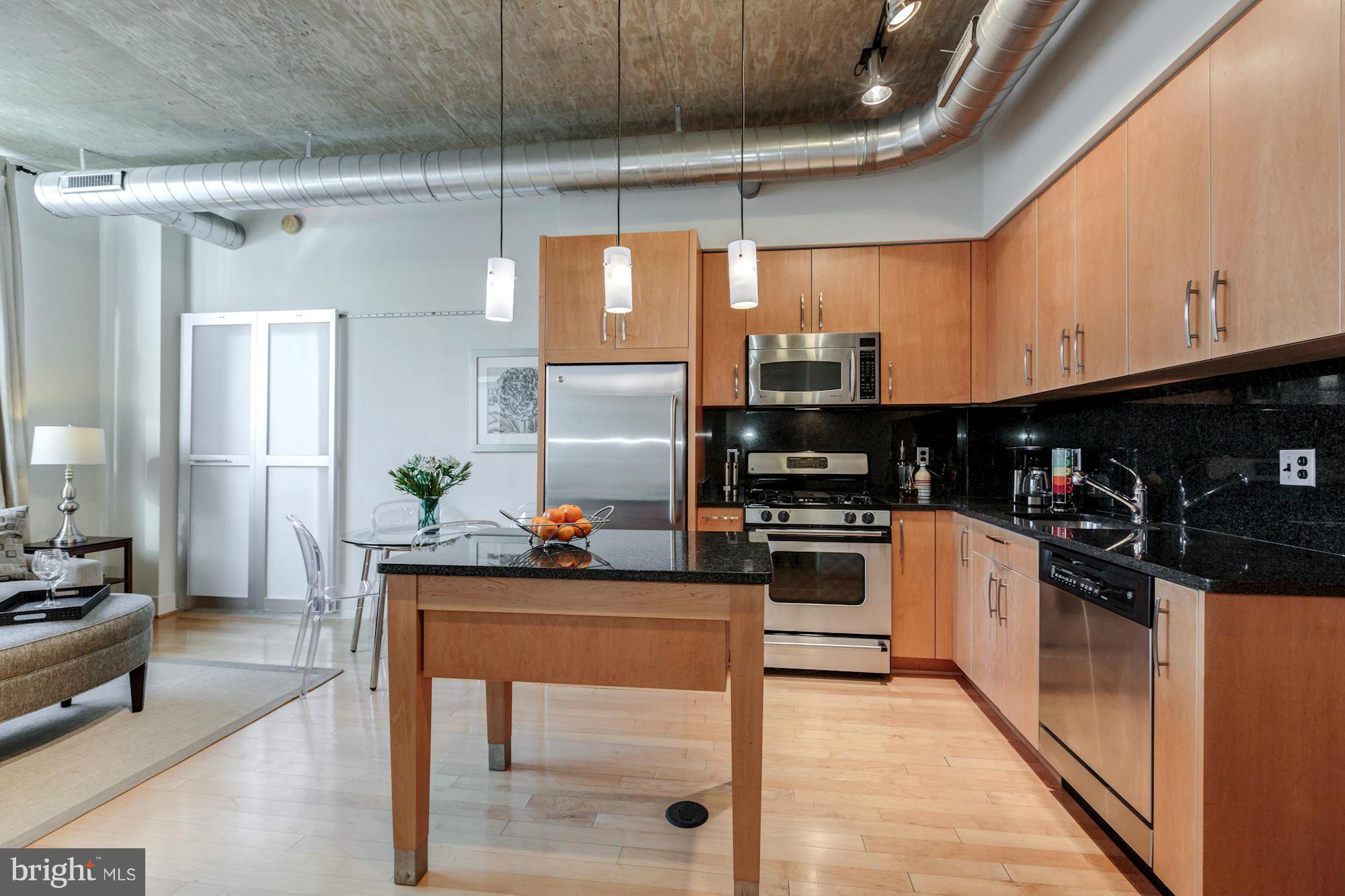 2301 Champlain Street Northwest, Unit 112 Washington, DC 20009 - Photo 11 of 29 a kitchen with stainless steel appliances kitchen island granite countertop a refrigerator and a stove top oven