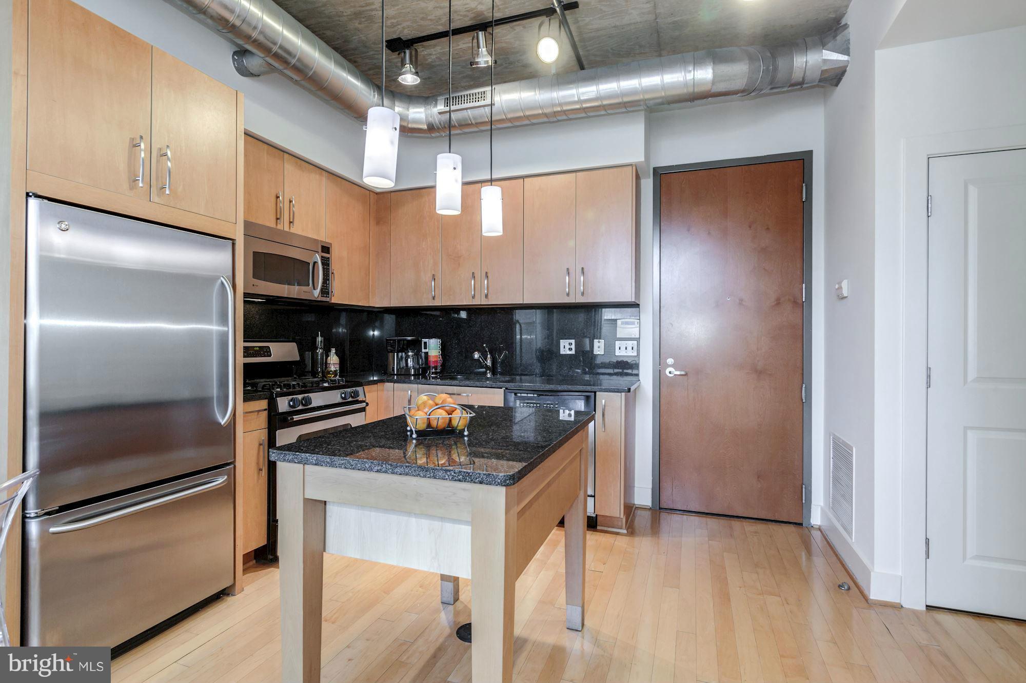 2301 Champlain Street Northwest, Unit 112 Washington, DC 20009 - Photo 10 of 29 a kitchen with stainless steel appliances granite countertop a refrigerator a stove and a sink with wooden floor