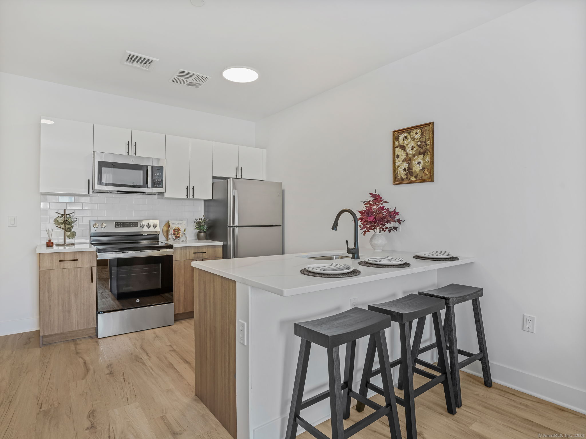 821 East Main Street, Unit 209 Stamford, CT 06902 - Photo 11 of 29 a kitchen with a table chairs refrigerator and microwave