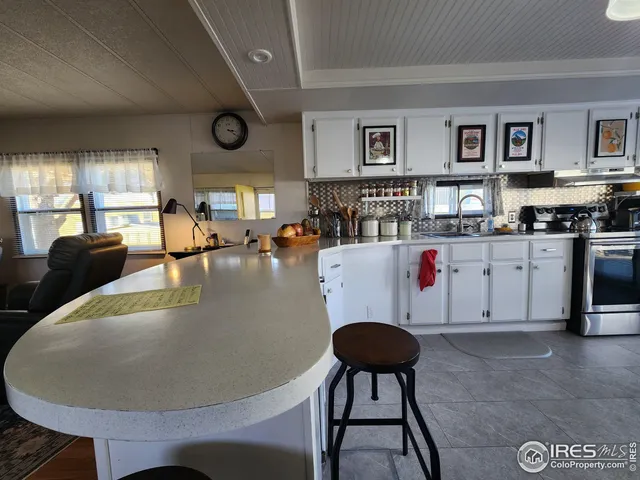 a living room with stainless steel appliances granite countertop a couch a dining table and chairs next to a window