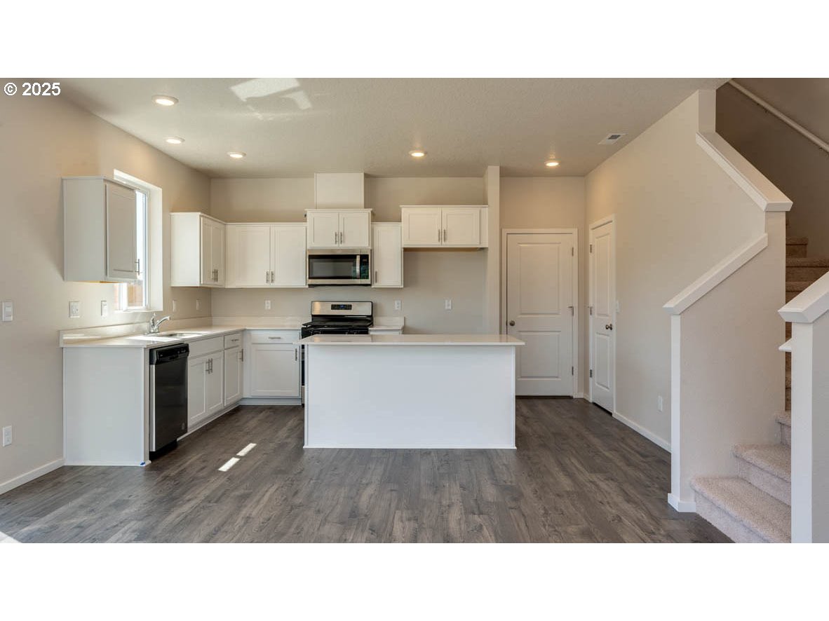 2873 V Street Springfield, OR 97477 - Photo 4 of 22 a kitchen with stainless steel appliances kitchen island granite countertop a stove a sink a refrigerator and white cabinets
