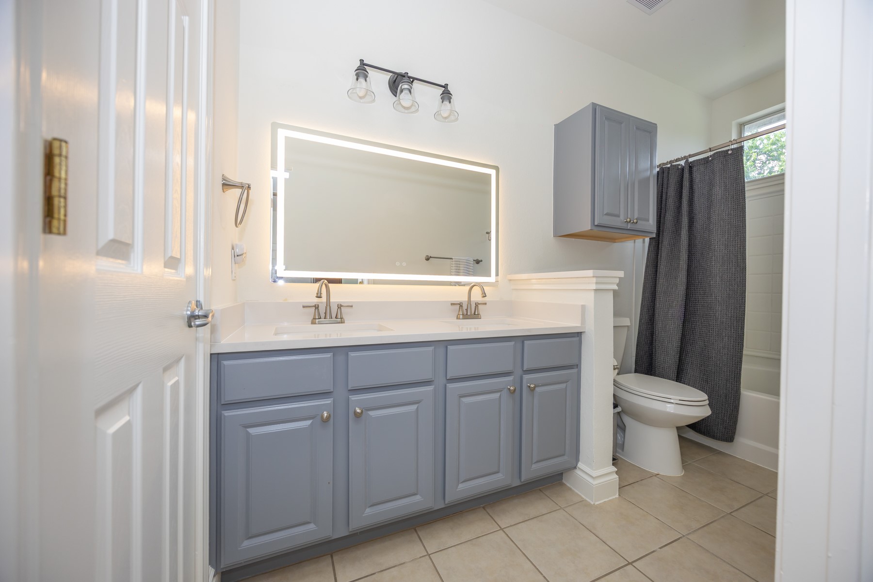 11500 Dimmit Street Manor, TX 78653 - Photo 9 of 14 Bathroom featuring a double vanity with light gray cabinetry, a white countertop, and an illuminated mirror