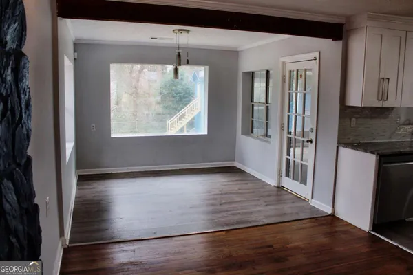 a view of a hallway with wooden floor and a living room