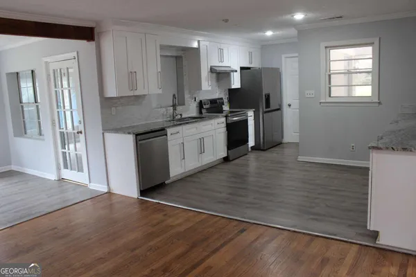 a kitchen with granite countertop a refrigerator stove and wooden floor