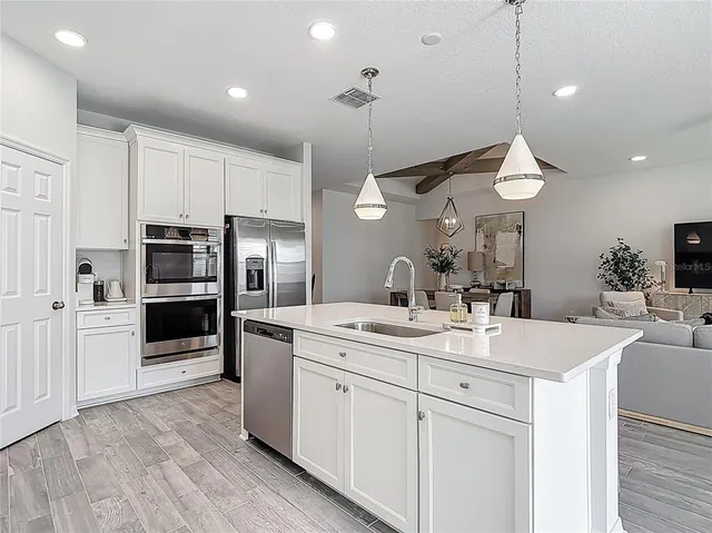 a kitchen with stainless steel appliances granite countertop a sink a stove a refrigerator and island with wooden floor