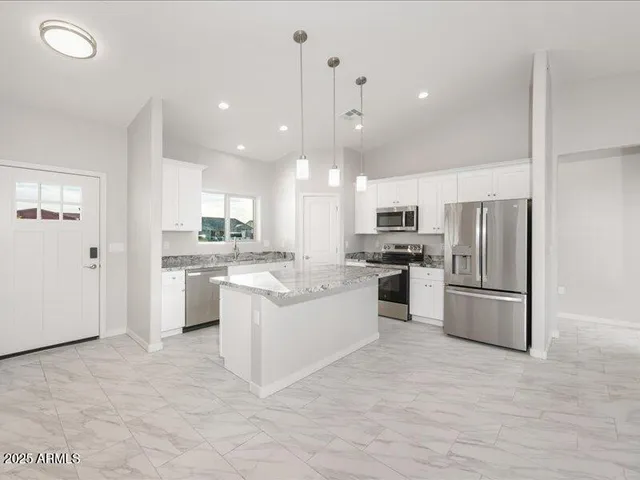 a large kitchen with white cabinets stainless steel appliances and a center island
