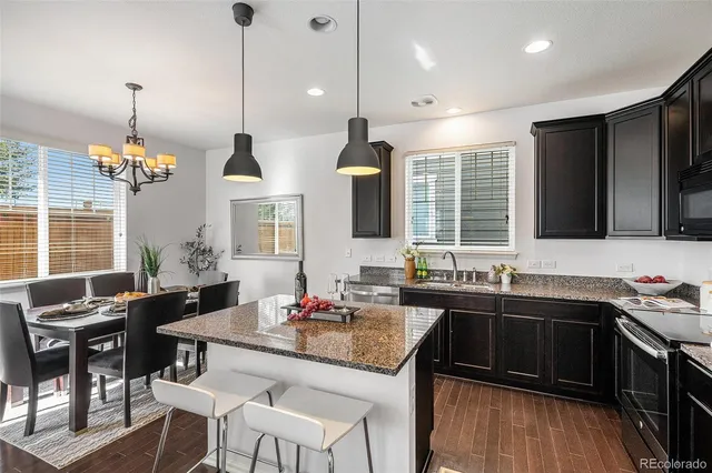 a kitchen with stainless steel appliances granite countertop a sink a stove and a wooden floor