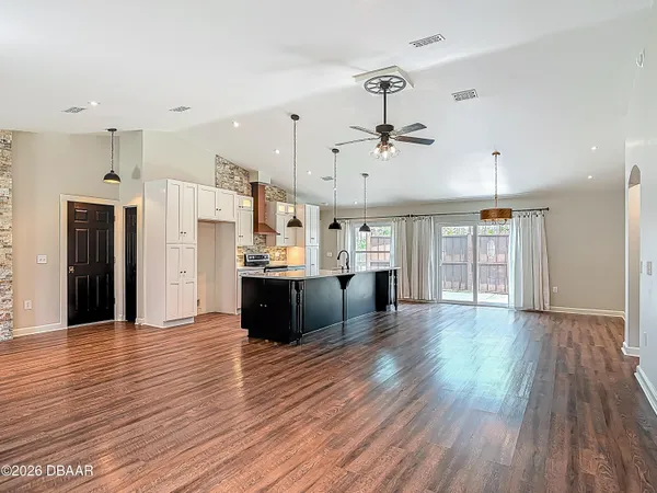 an empty room with wooden floor fireplace and windows