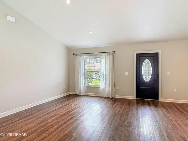 a living room with stainless steel appliances wooden floor and a fireplace