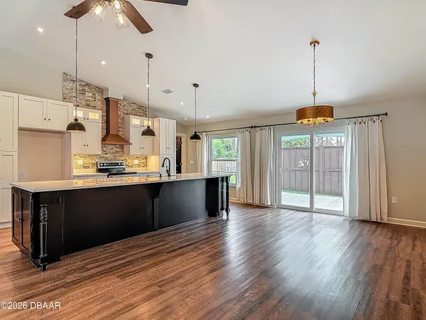 a kitchen with stainless steel appliances granite countertop a sink a stove and a wooden floor