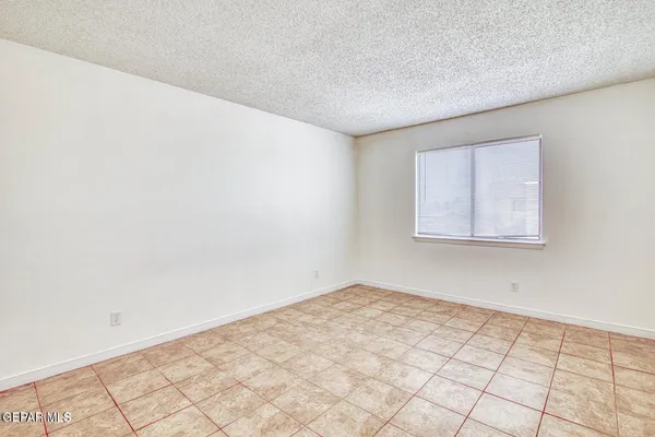 an empty room with a chandelier fan and windows