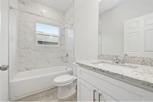 a bathroom with a granite countertop sink a toilet and bathtub