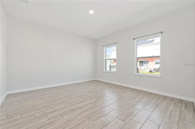 an empty room with wooden floor and windows
