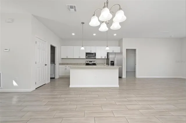 a large kitchen with stainless steel appliances granite countertop a large counter top a stove a refrigerator and cabinets