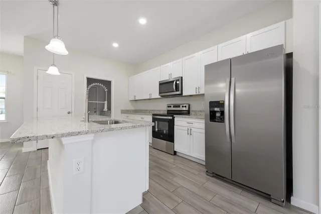 a kitchen with kitchen island granite countertop stainless steel appliances a sink and a refrigerator