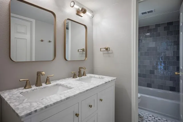 a bathroom with a granite countertop sink a mirror and a bathtub