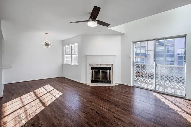 a view of an empty room with wooden floor fireplace and a window