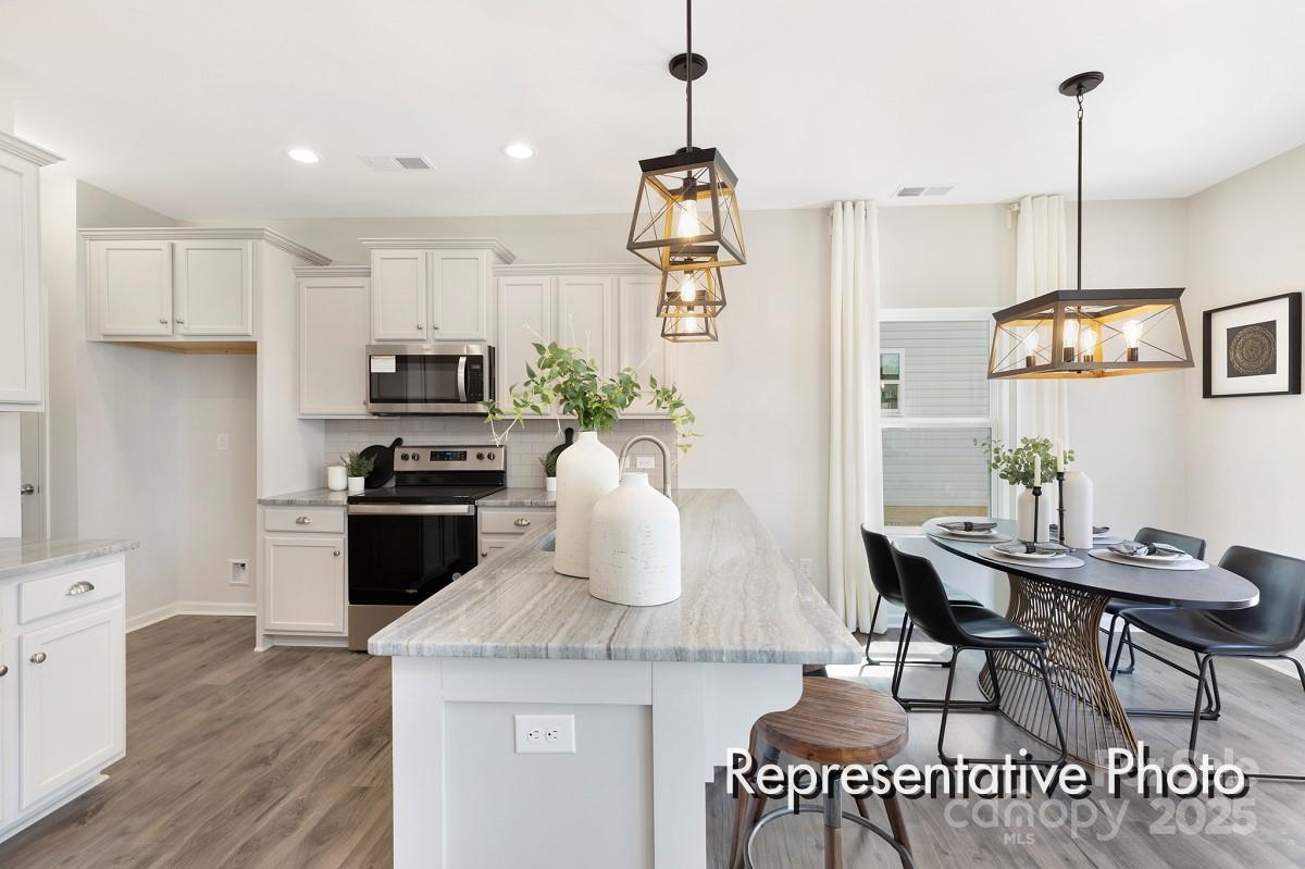 12540 Gotland Road, Unit 329 Midland, NC 28107 - Photo 5 of 22 a kitchen with a table chairs refrigerator and microwave