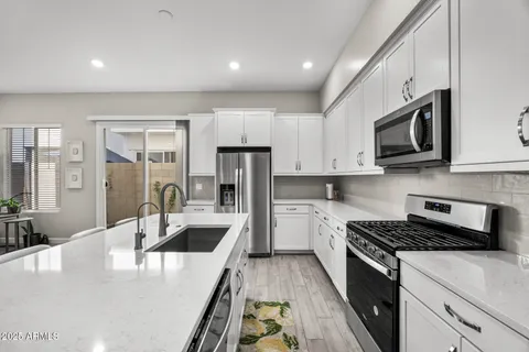 a kitchen with stainless steel appliances granite countertop a dining table chairs refrigerator and microwave