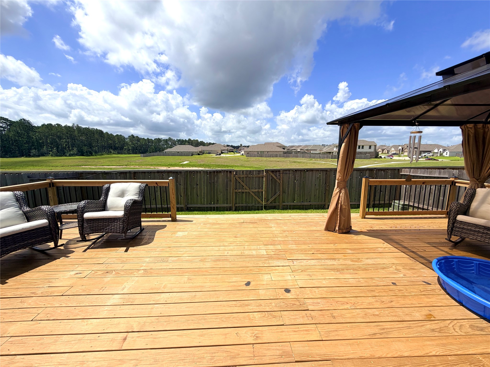 532 Flower Reed Court Magnolia, TX 77354 - Photo 29 of 43 The backyard has a spacious wooden deck with comfortable seating, a covered gazebo, and expansive views of the retention pond and neighboring homes. Ideal for outdoor relaxation and entertaining.