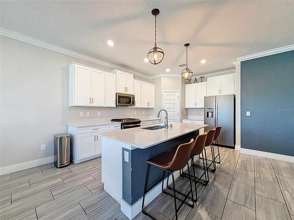 8124 Olympic Stone Circle Trinity, FL 34655 - Photo 16 of 75 a kitchen with stainless steel appliances a stove a sink island and a refrigerator