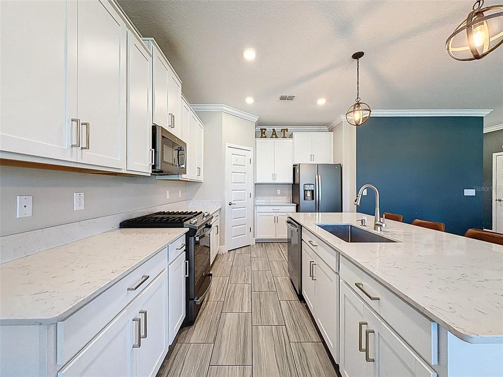 8124 Olympic Stone Circle Trinity, FL 34655 - Photo 19 of 75 a kitchen with stainless steel appliances granite countertop a sink a stove and a wooden floors