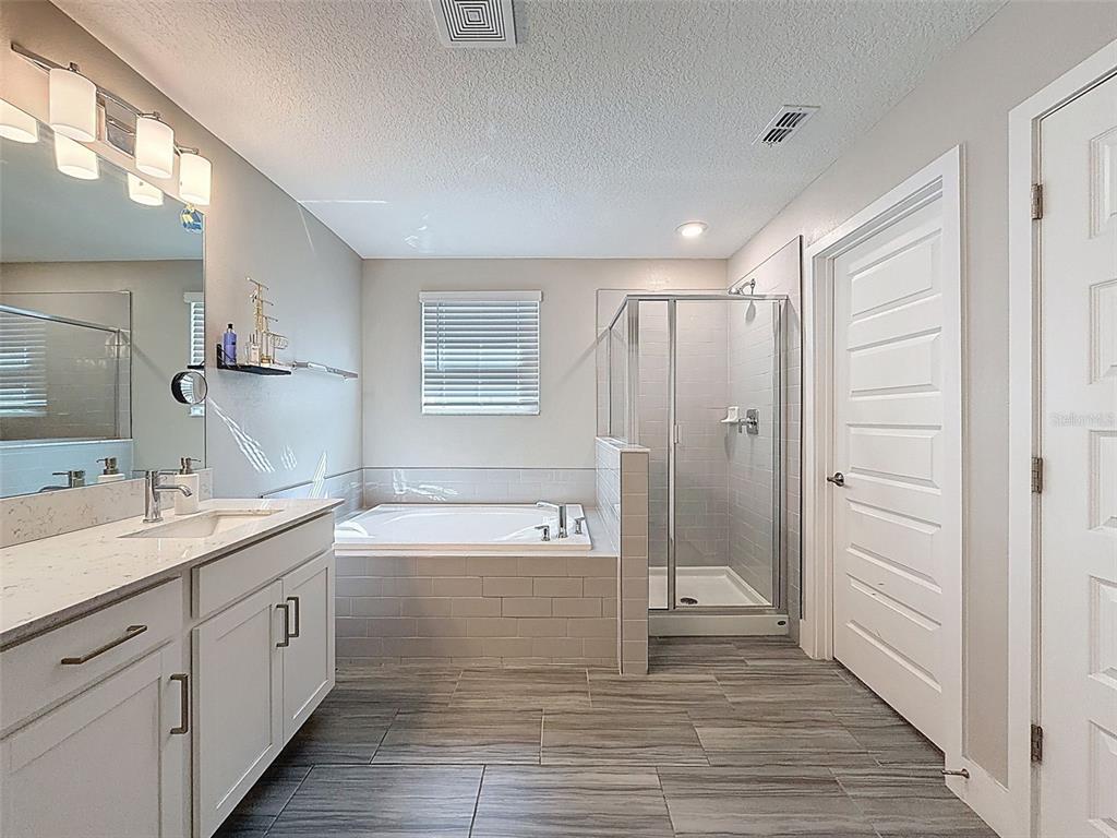 8124 Olympic Stone Circle Trinity, FL 34655 - Photo 39 of 75 a spacious bathroom with a double vanity sink a mirror and a bathtub