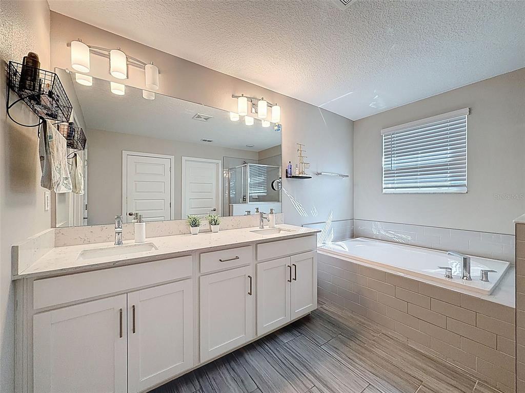 8124 Olympic Stone Circle Trinity, FL 34655 - Photo 41 of 75 a bathroom with a double vanity sink a mirror and a bathtub