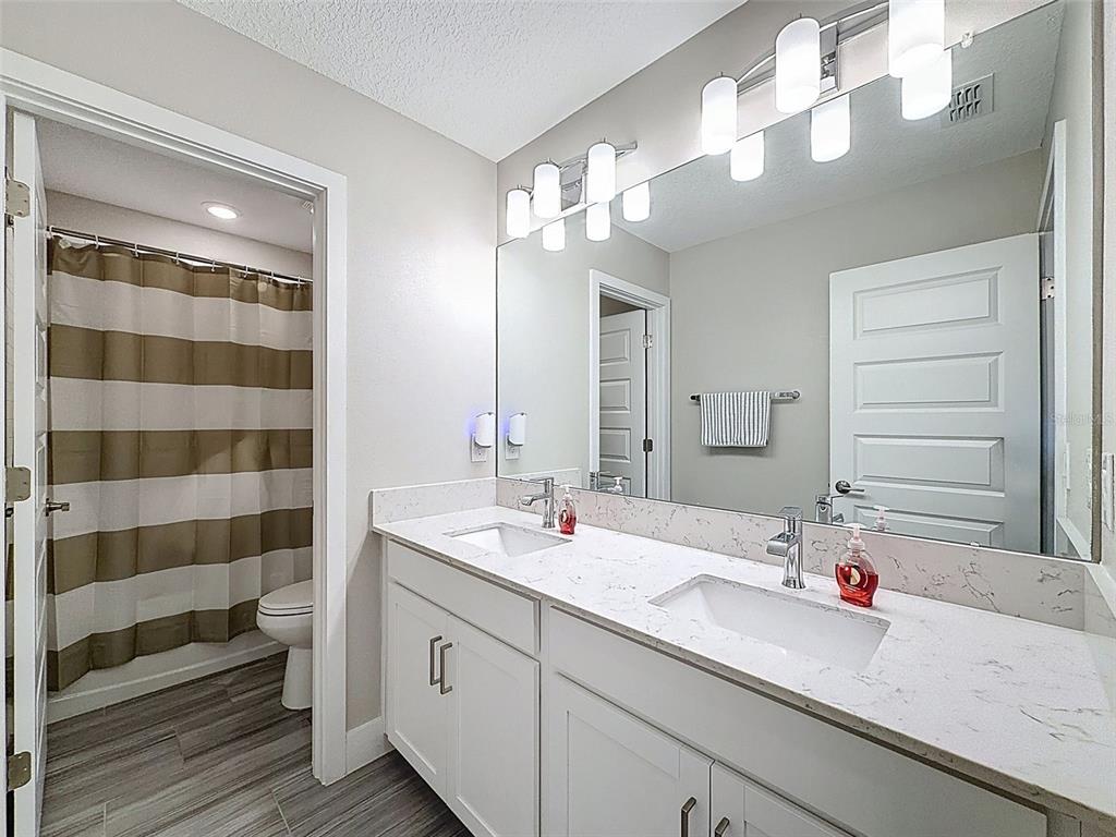 8124 Olympic Stone Circle Trinity, FL 34655 - Photo 50 of 75 a bathroom with a sink a large mirror and a shower