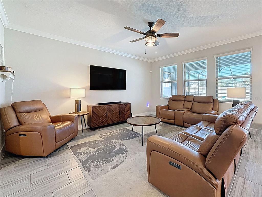 8124 Olympic Stone Circle Trinity, FL 34655 - Photo 10 of 75 a living room with furniture ceiling fan and a flat screen tv