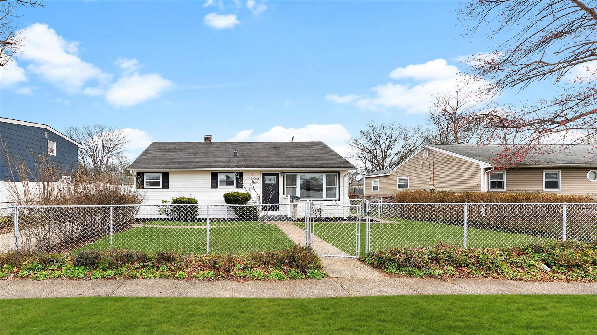44 East Somerset Road Amityville, NY 11701 - Photo 1 of 1 View of front facade with a front yard, a chimney, a gate, and a fenced front yard