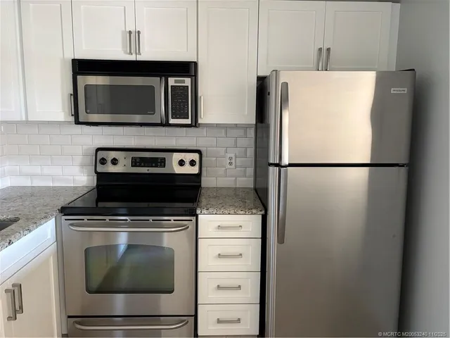 a white refrigerator freezer and a stove sitting inside of a kitchen