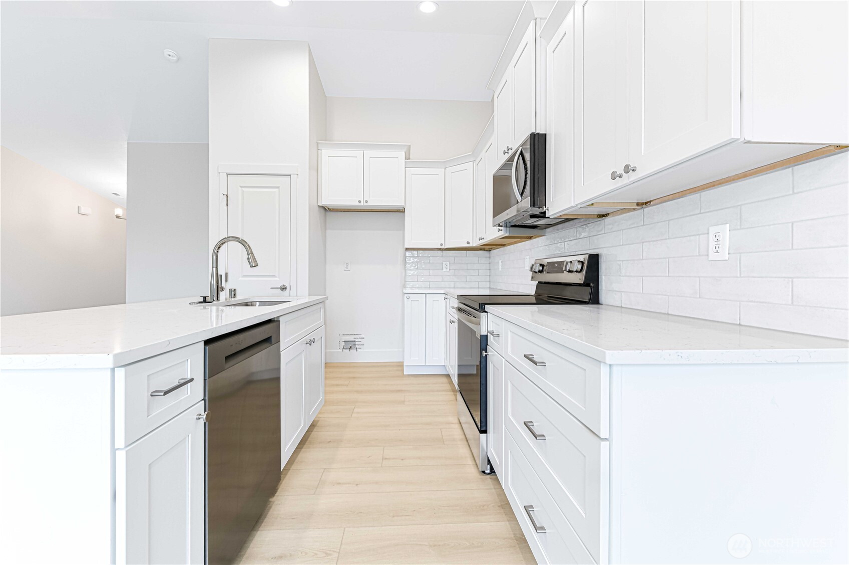 4259 Sandy Street Moses Lake, WA 98837 - Photo 8 of 21 a kitchen with stainless steel appliances a sink dishwasher stove refrigerator and white cabinets with wooden floor
