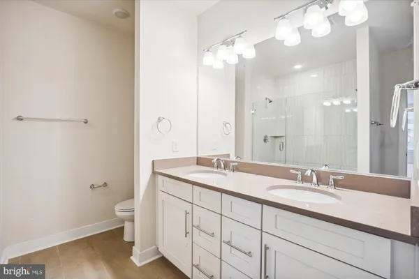 a bathroom with a granite countertop double vanity sink a mirror and a toilet