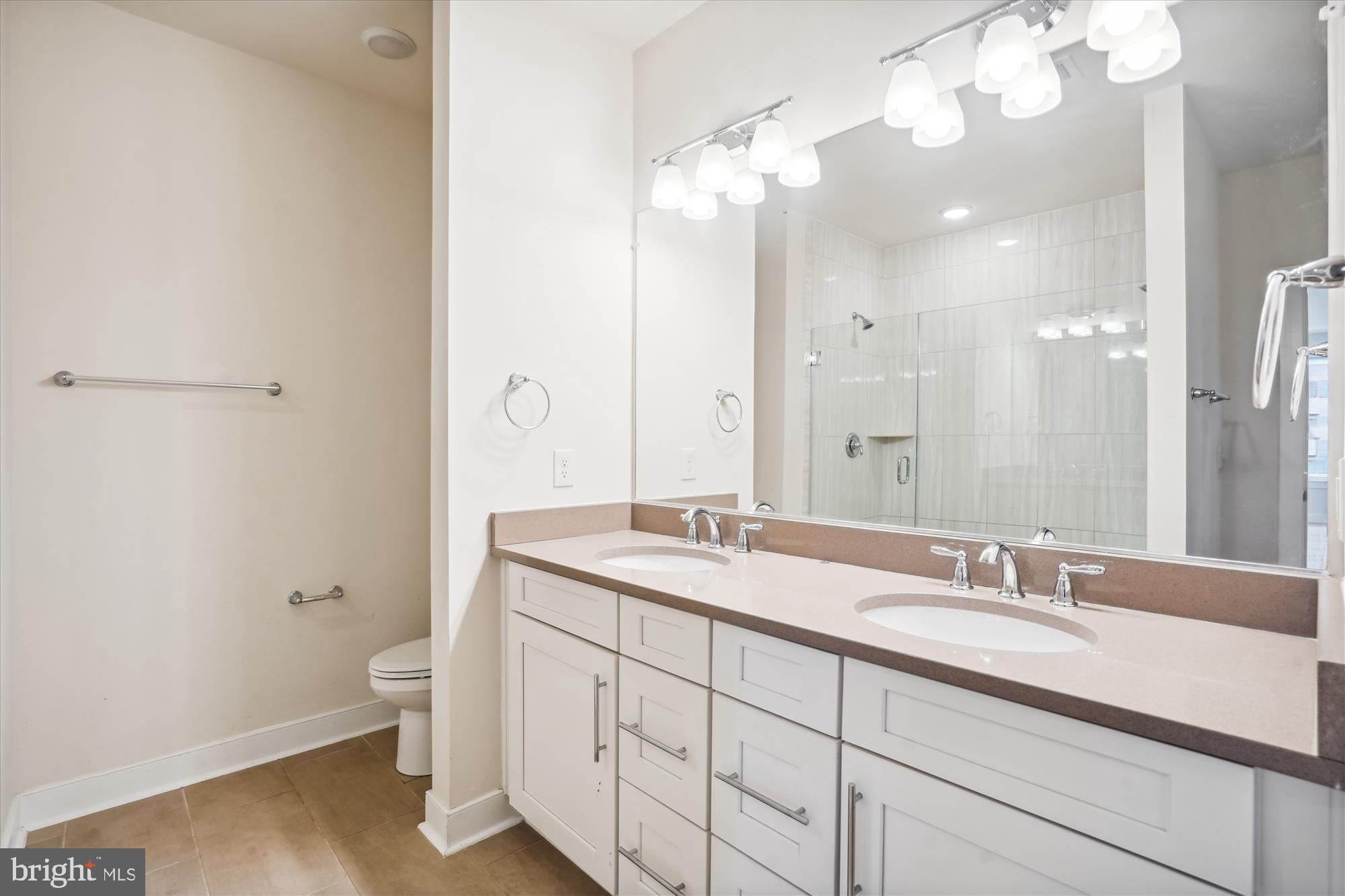 11200 Reston Station Boulevard, Unit 306 Reston, VA 20190 - Photo 15 of 53 a bathroom with a granite countertop double vanity sink a mirror and a toilet
