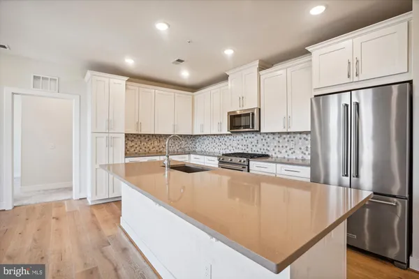a kitchen with stainless steel appliances granite countertop a refrigerator a stove and a sink